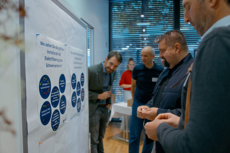 Teilnehmerinnen stehen bei einer Matchmaking vor einer Pinnwand und diskutieren die Inhalte.